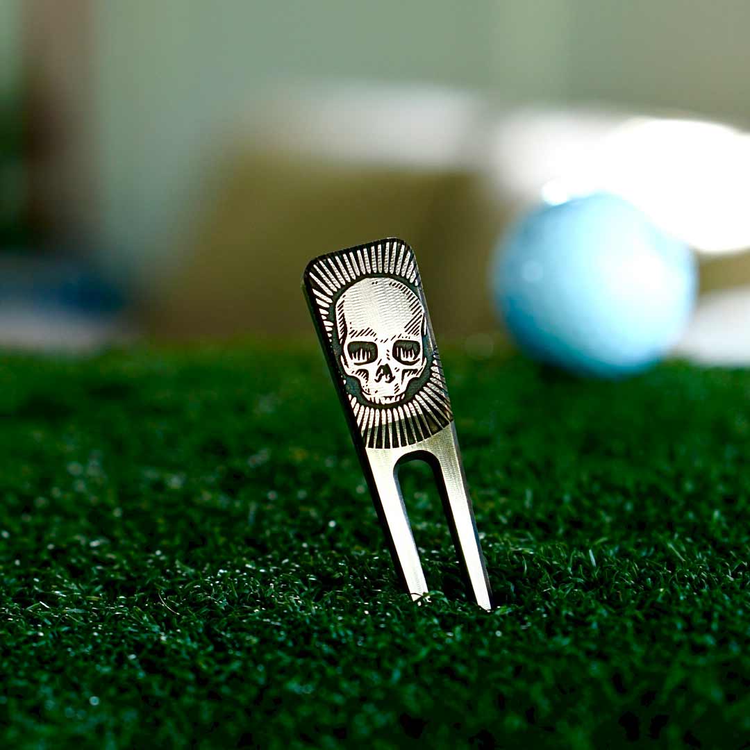Skull-shaped divot tool embedded in the putting green - bold design by Kraken Golf