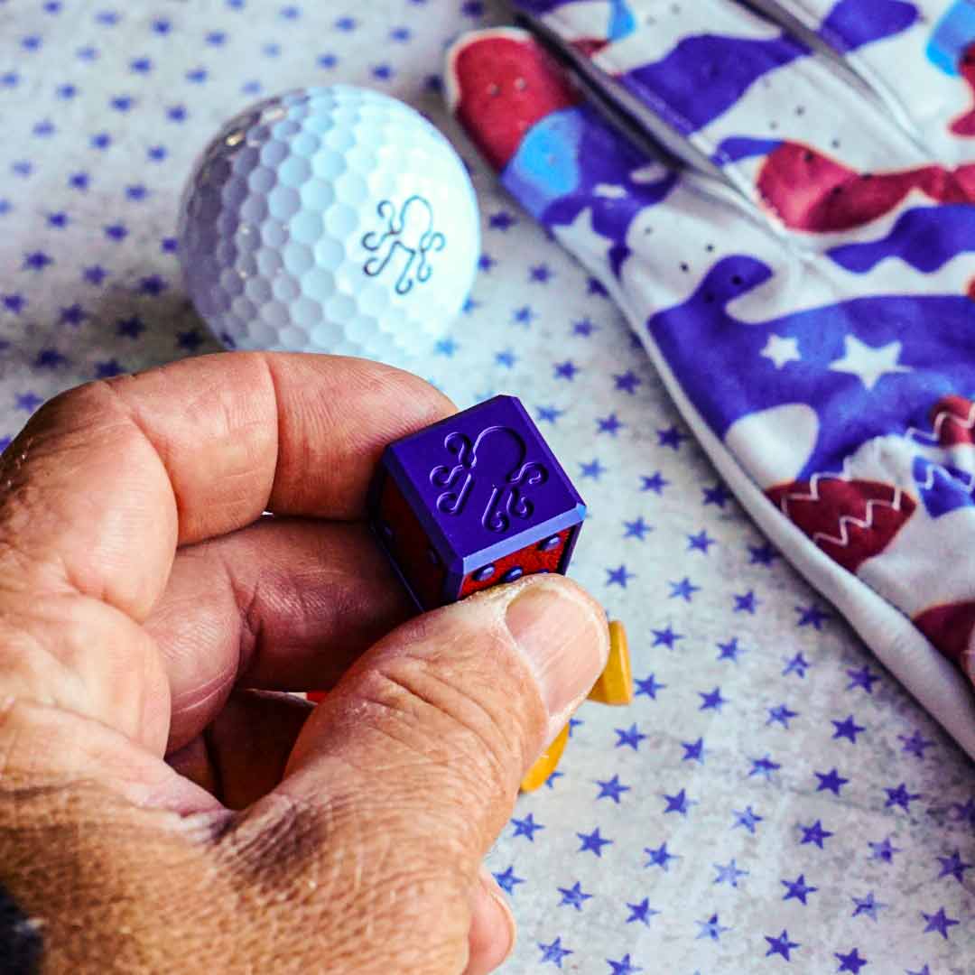 A royal blue cube-shaped golf ball marker with red, white, and blue leather inlays. Limited edition Kraken Golf die crafted for the 4th of July.