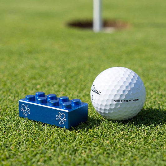 Cobalt blue Brix ball marker resting beside a Titleist Pro V1 on a manicured putting green