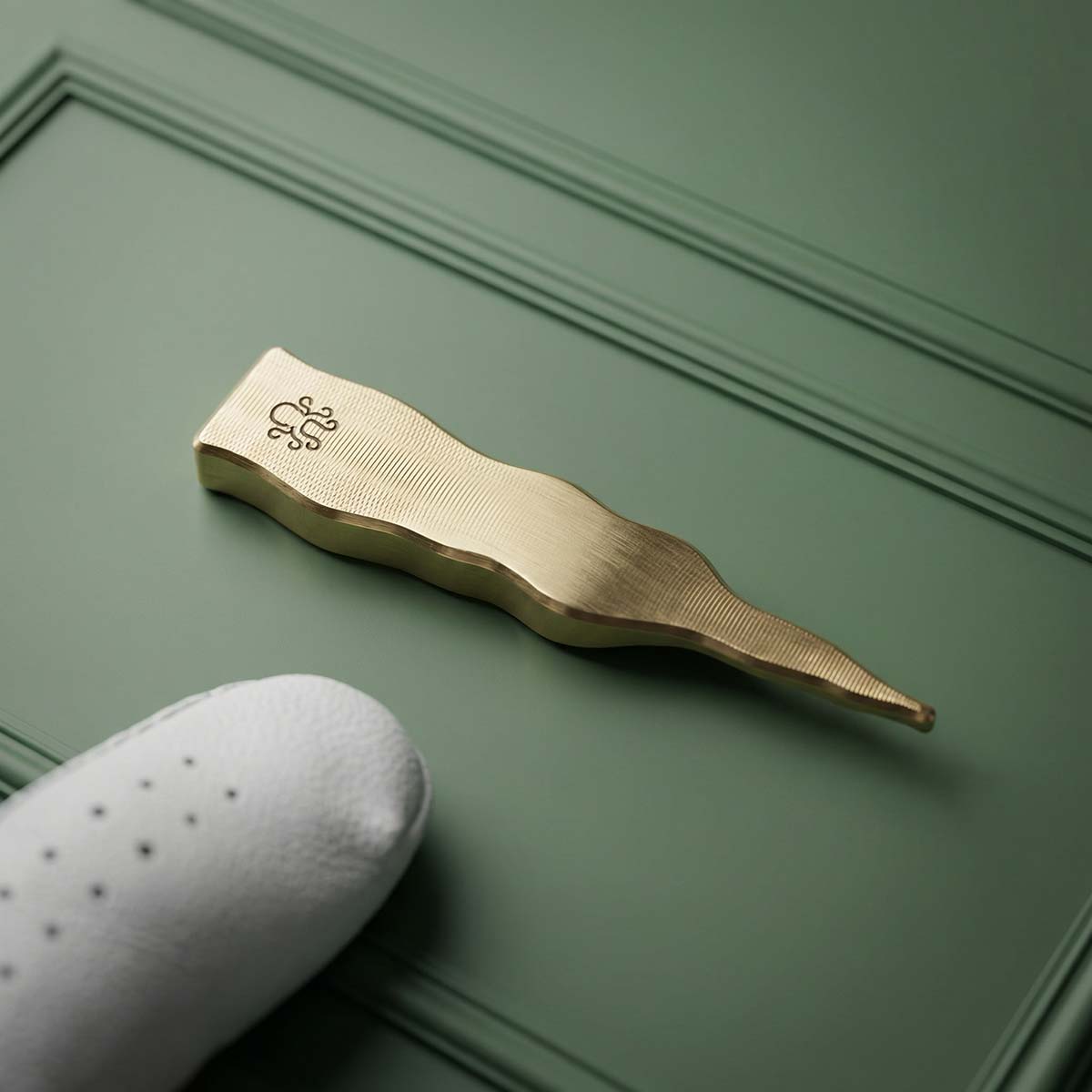 Back of brass pennant pitch tool with Kraken Golf logo