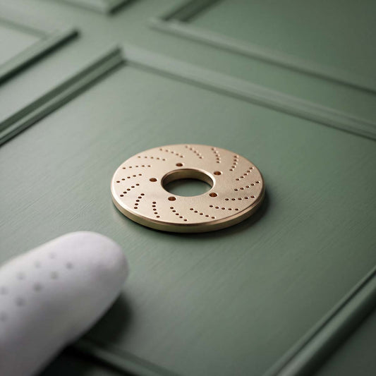 Brass roto golf ball marker on a green surface with a white glove partially visible