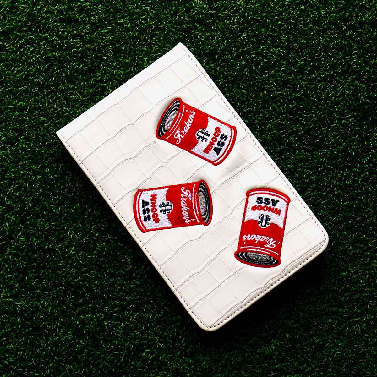 White crocodile embossed golf yardage book holder with embroidered Whoop Ass cans - front cover