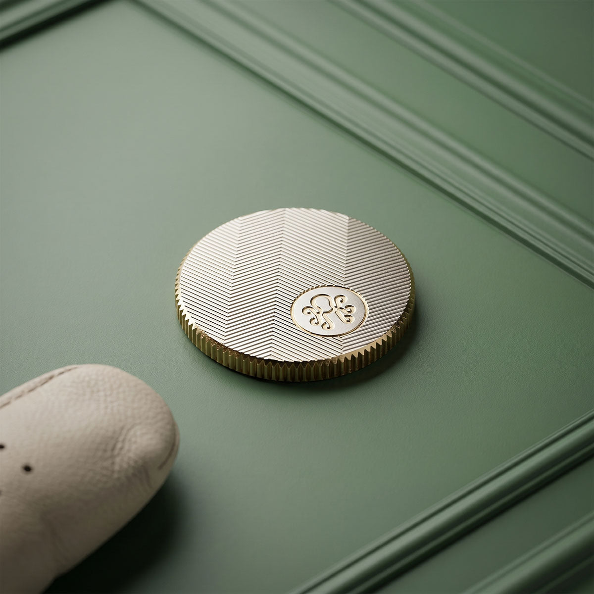 Back of The Gold Tooth golf ball marker with recessed Kraken monogram medallion on milled brass