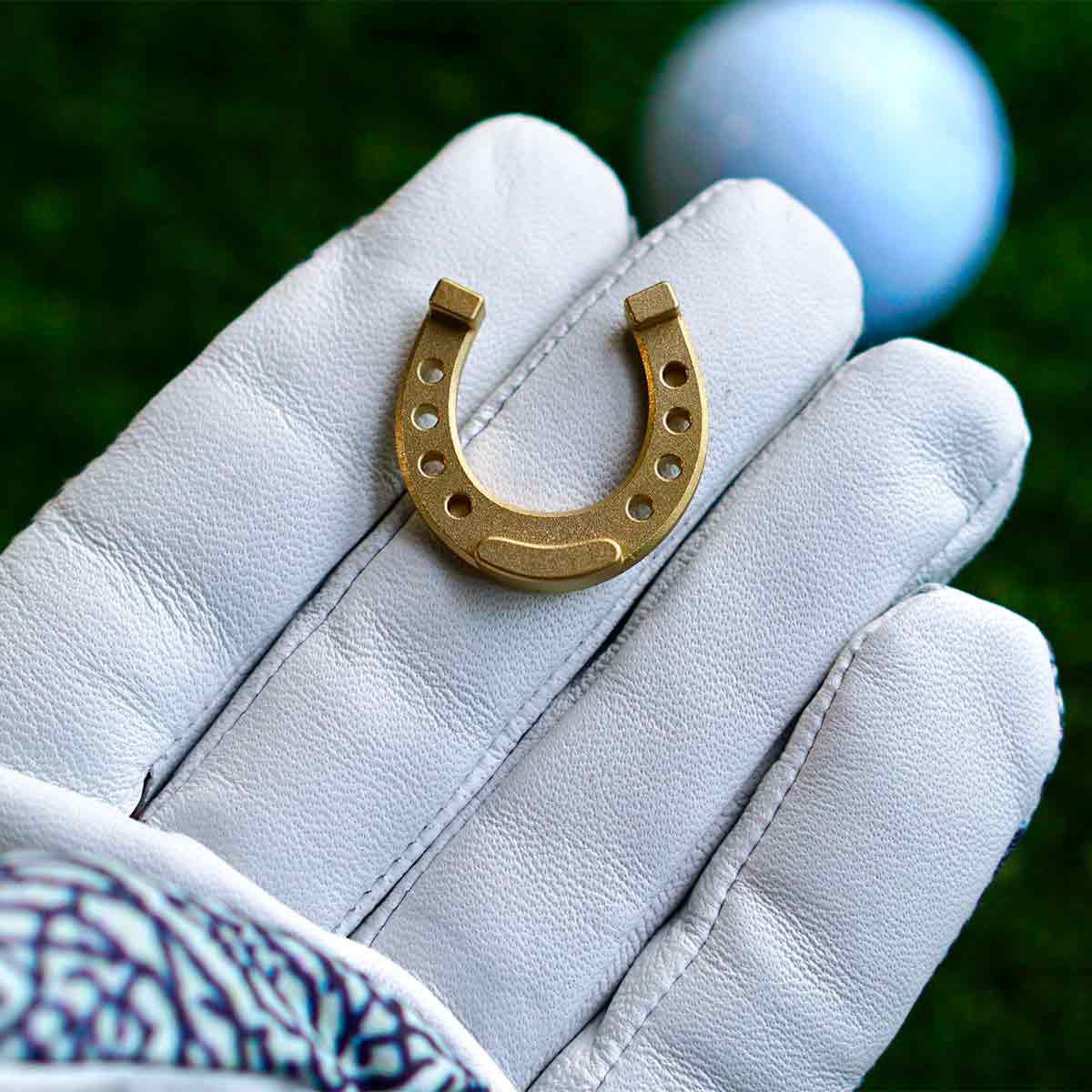 Brass horseshoe golf ball marker with engraved detail, heirloom design by Kraken Golf