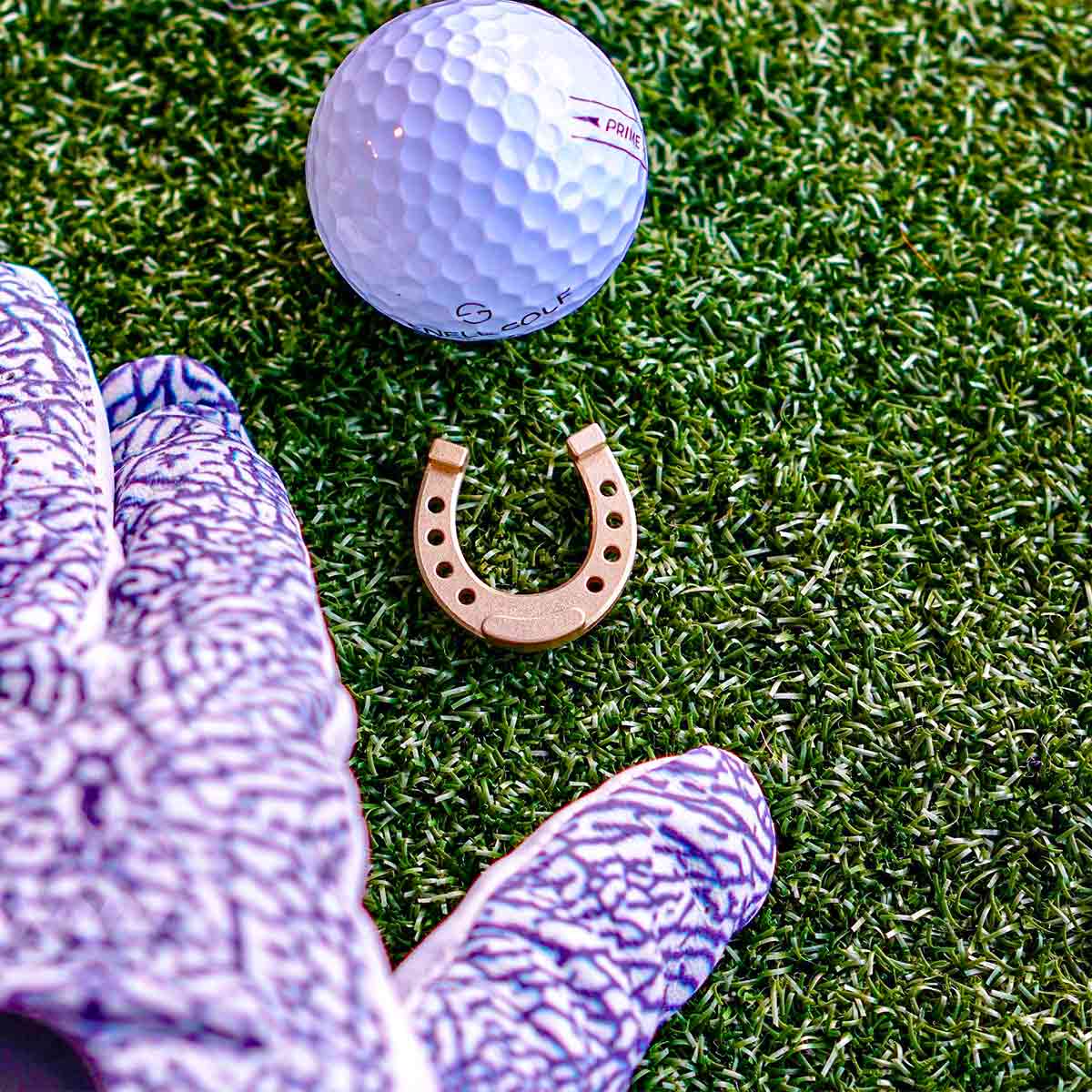 Lucky Horseshoe golf ball marker on the putting green, PLAY BOLD Kraken Golf drop