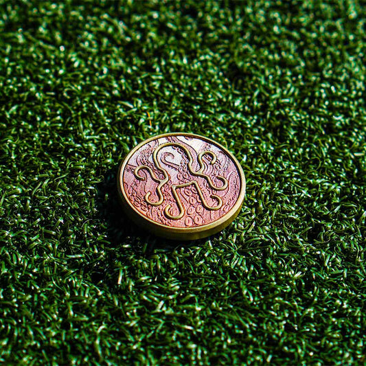 Leviathan golf ball marker front view with copper Kraken tentacle inlay on brass