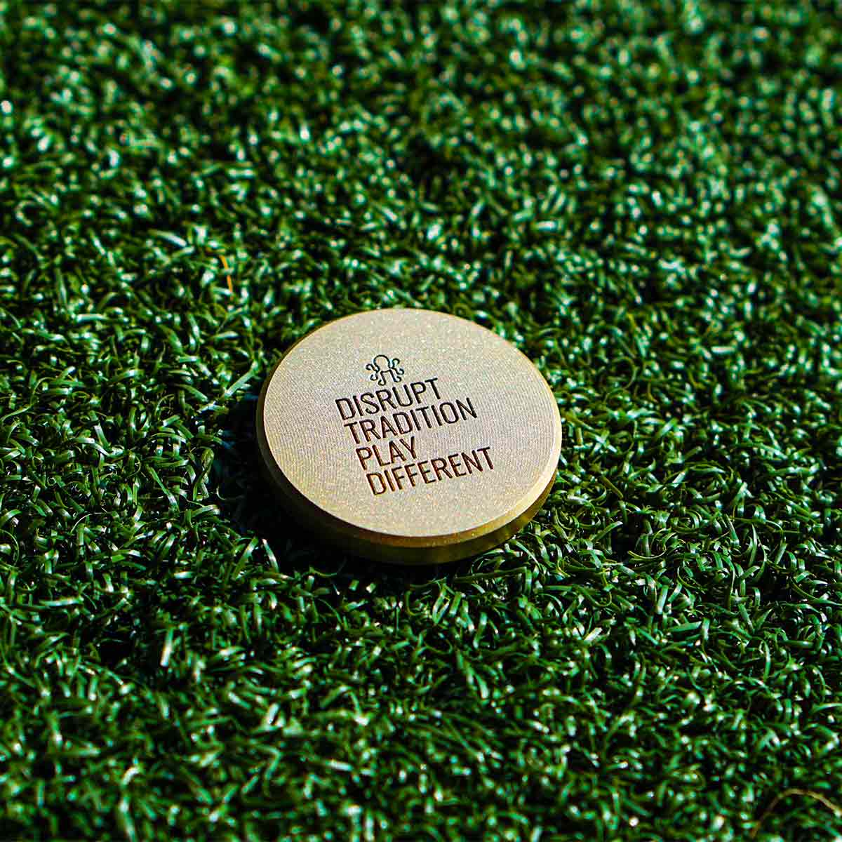 Back of Leviathan golf marker with satin brass finish and engraved motto DISRUPT TRADITION PLAY DIFFERENT