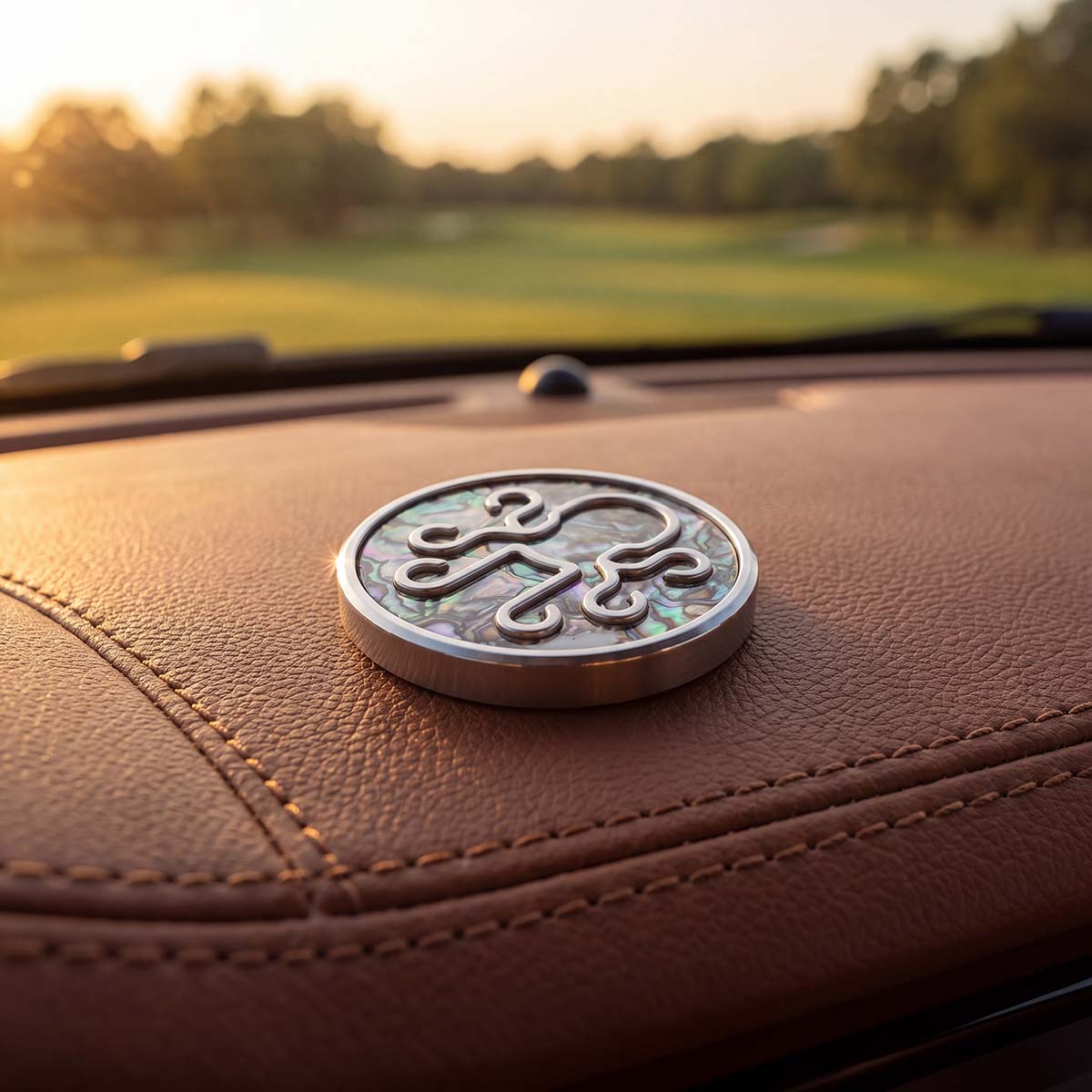 NACRE golf ball marker with iridescent abalone shell inlay and raised stainless steel Kraken logo on a golf cart