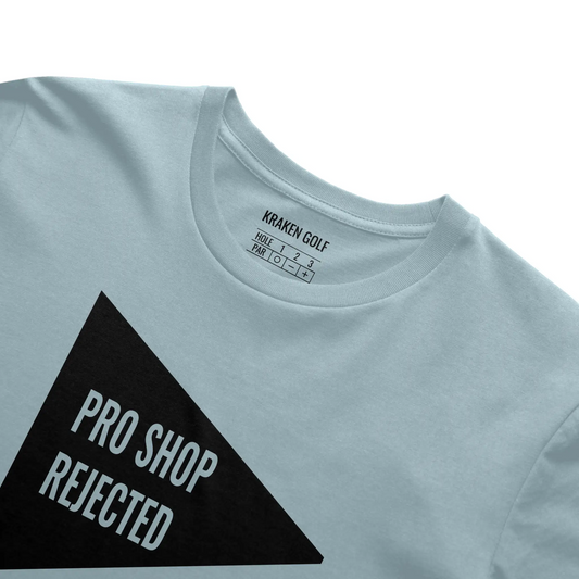 Close-up of the Pro Shop Rejected premium golf t-shirt in Harbor blue — black triangular flag graphic and Kraken Golf Co. inner neck tag detail