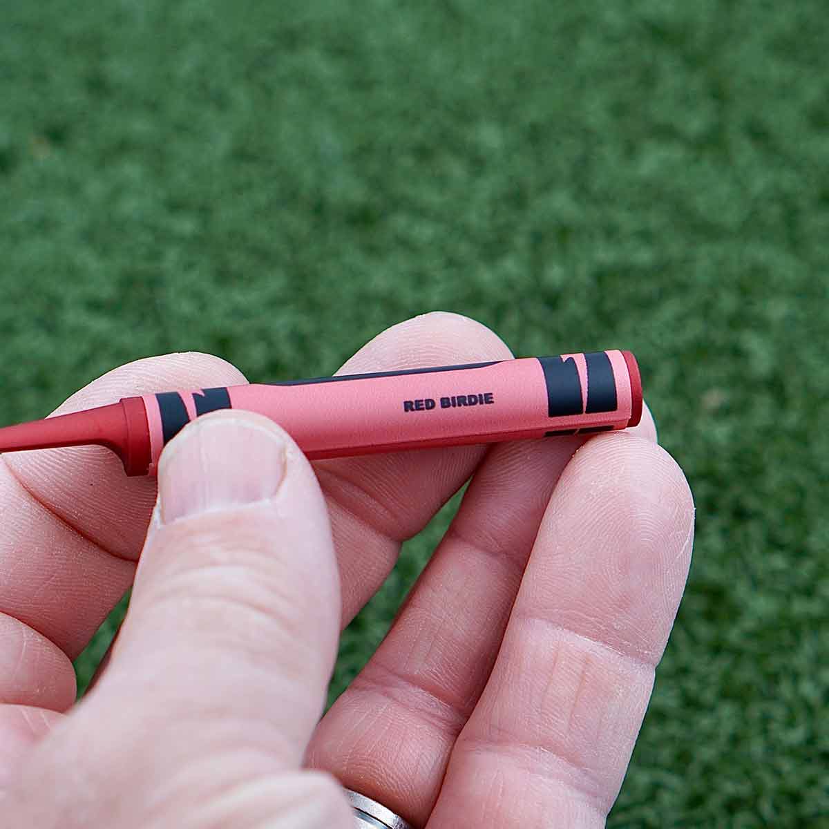 Kraken Golf Red Birdie divot tool beside ball marker and golf ball on green