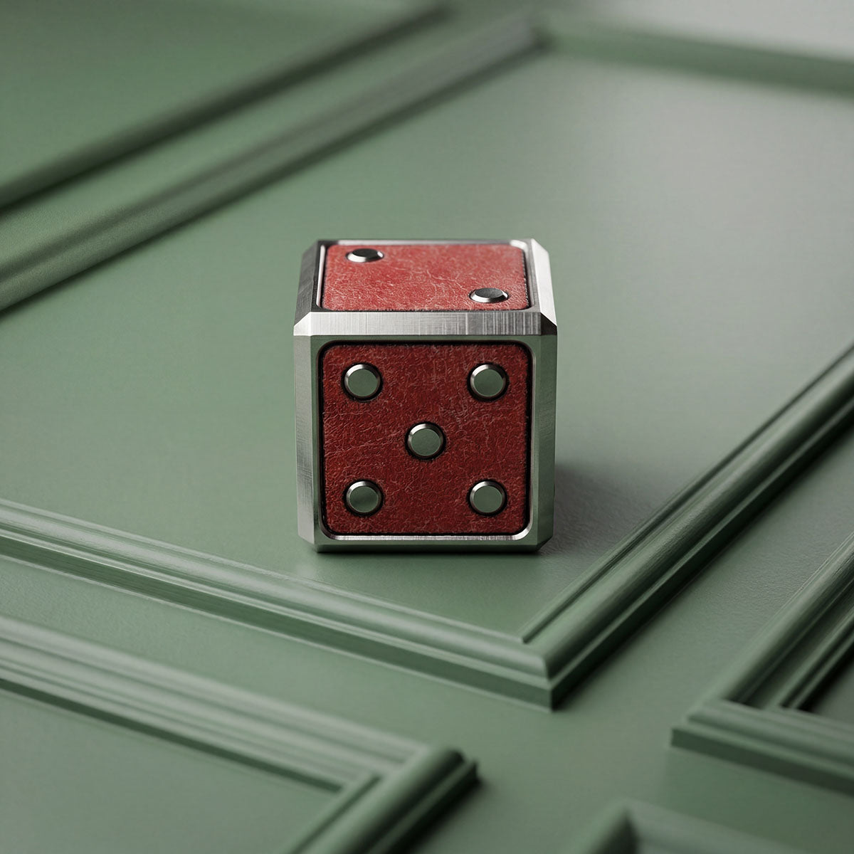 Snake Eyes ball marker resting against sage green paneled wall.