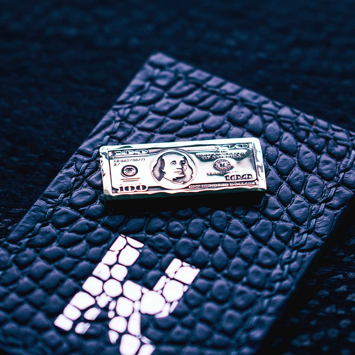 Brass golf ball marker shaped like a $100 bill with hand-hammered edges

