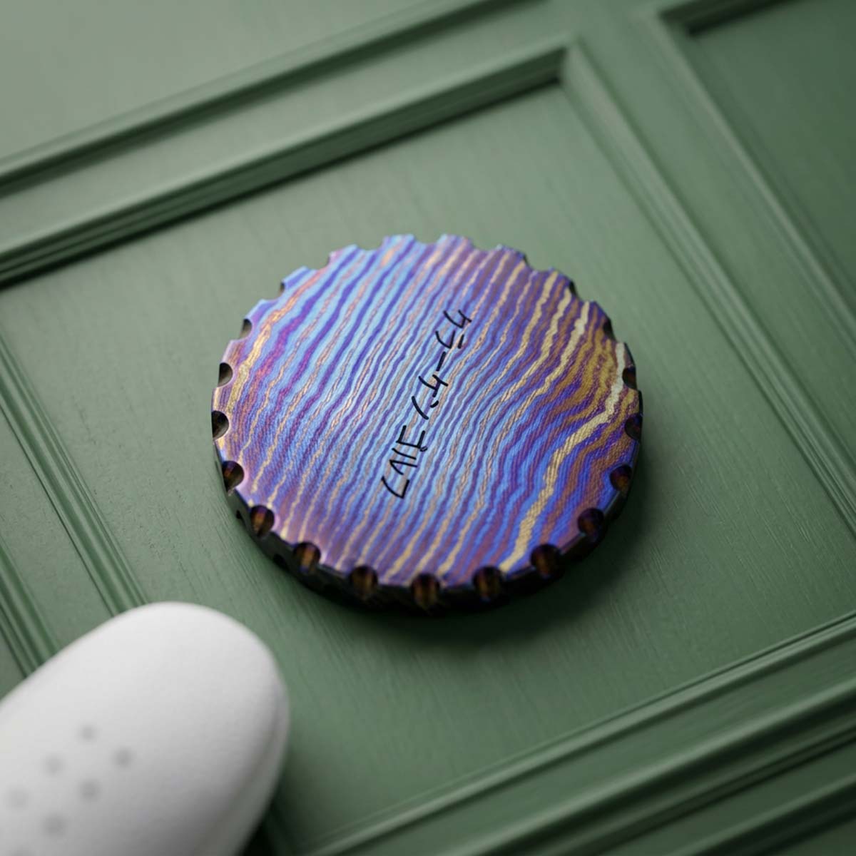 Reverse of the Amaterasu ball marker showing the iridescent purple and gold timascus grain with KRAKEN in Japanese script