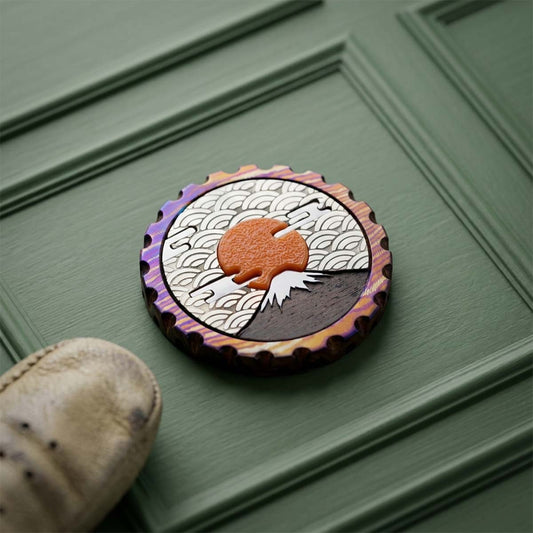 Amaterasu timascus golf ball marker with Mt. Fuji inlaid in stainless steel, brass sky with Japanese wave pattern, and a sculpted burnt-orange sun