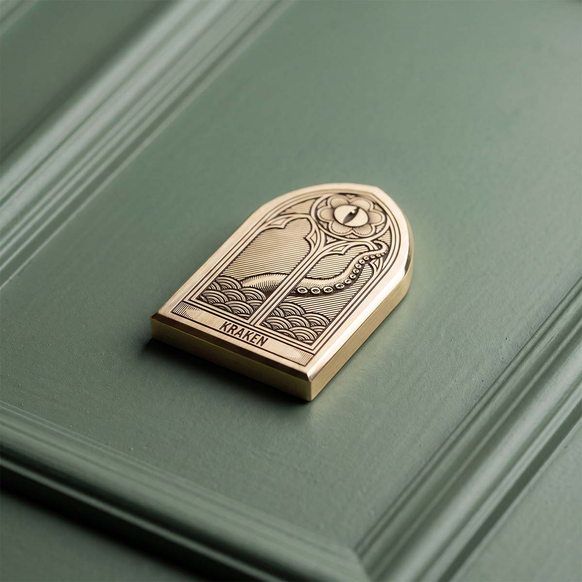 Solid brass gothic arch golf ball marker, brushed finish with engraved Kraken logo — Oculus by Kraken Golf