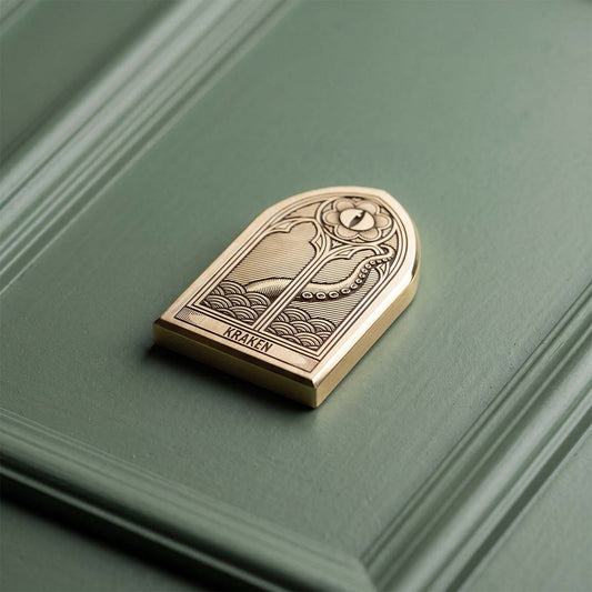 Solid brass gothic arch golf ball marker, brushed finish with engraved Kraken logo — Oculus by Kraken Golf