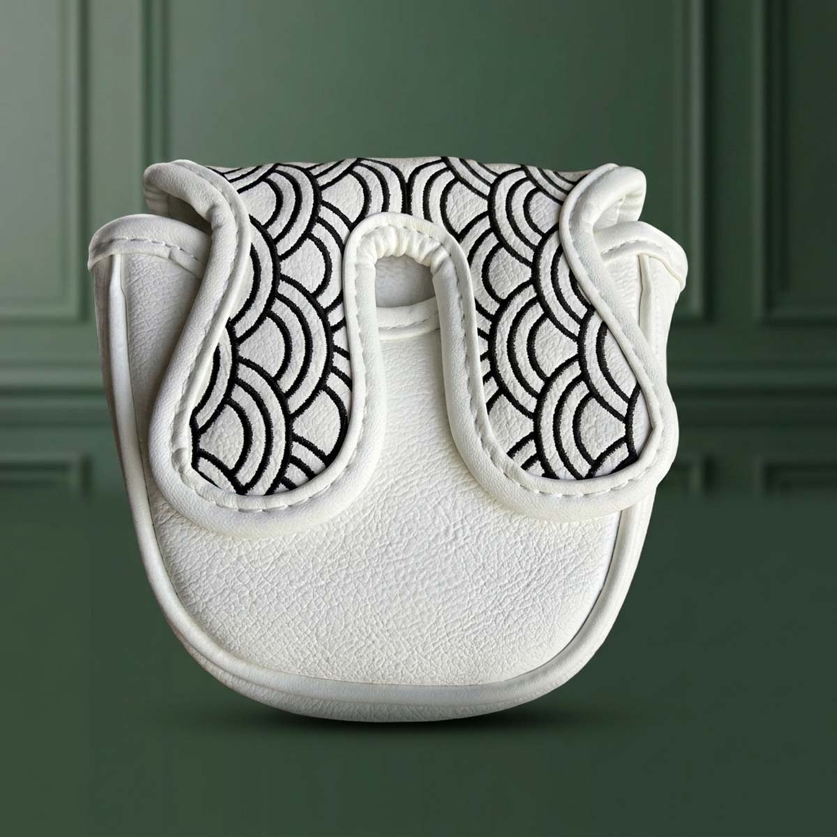 Angled view of white mallet putter headcover with full-coverage Japanese wave embroidery on green paneled wall