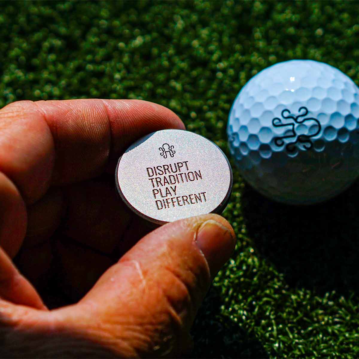 Back side of Shinkai ball marker showing Kraken logo detail on brushed stainless surface