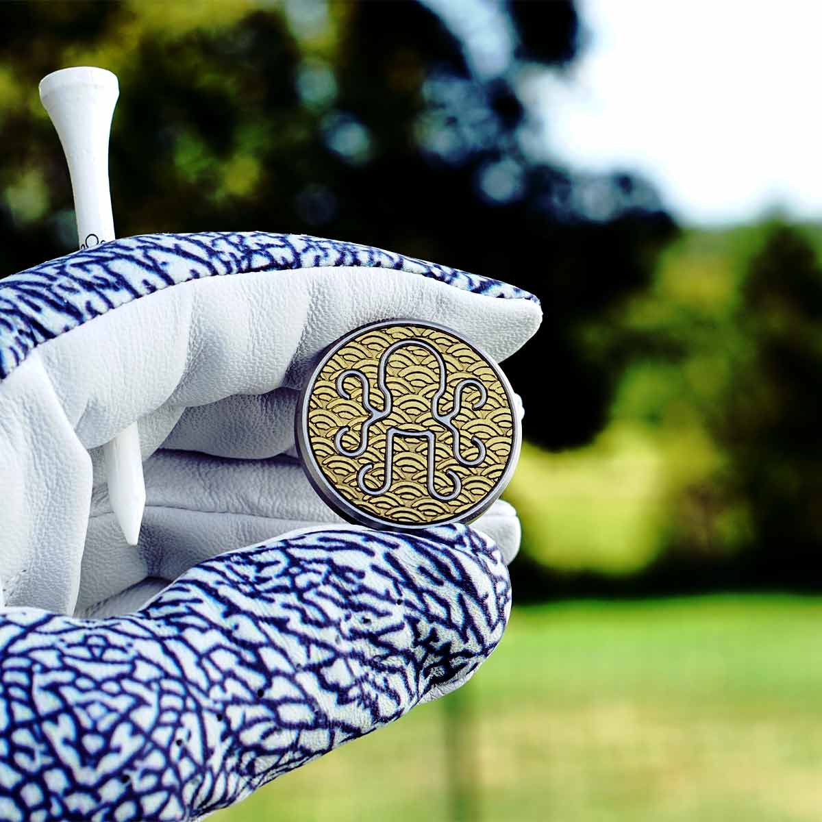 Golf glove holding the Shikai golf ball marker with a golf course in the background