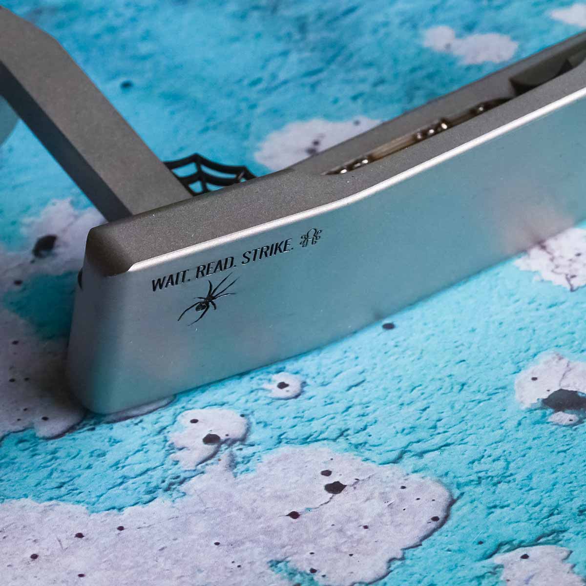 Sole of Arachne putter with WAIT. READ. STRIKE. engraving and Kraken logo