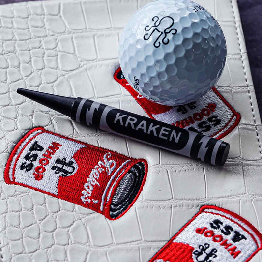 black crayon pitch tool from Kraken Golf on a leather yardage book