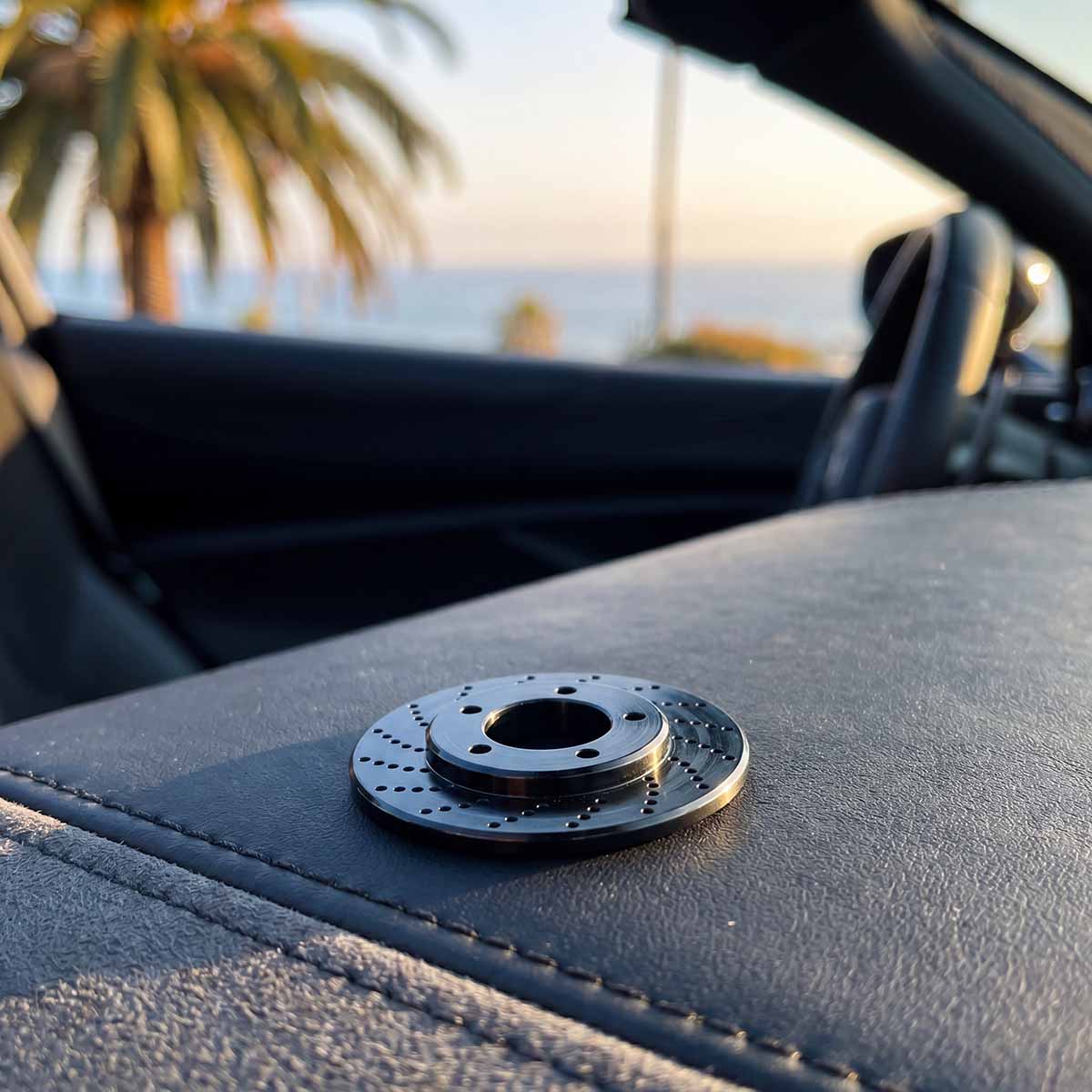 black rotor ball marker sitting on a leather car dash