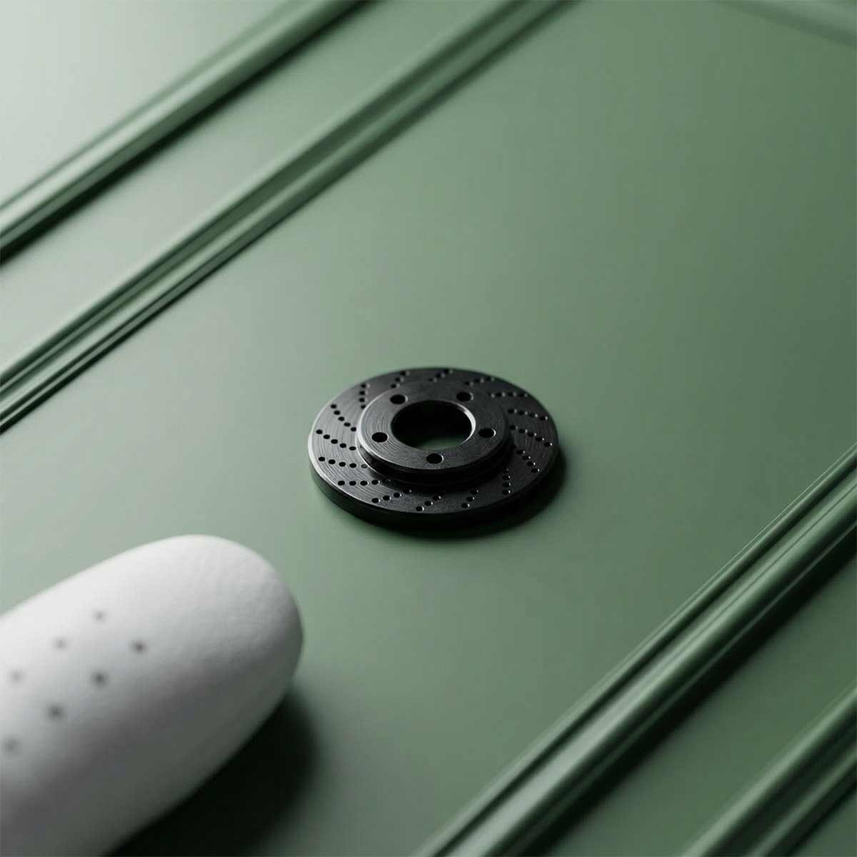black rotor shaped golf ball marker on a green background