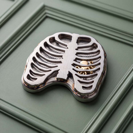 Heartless stainless steel rib cage golf ball marker with 14k gold Kraken visible through the ribs, Kraken Golf Blacklist No. 039
