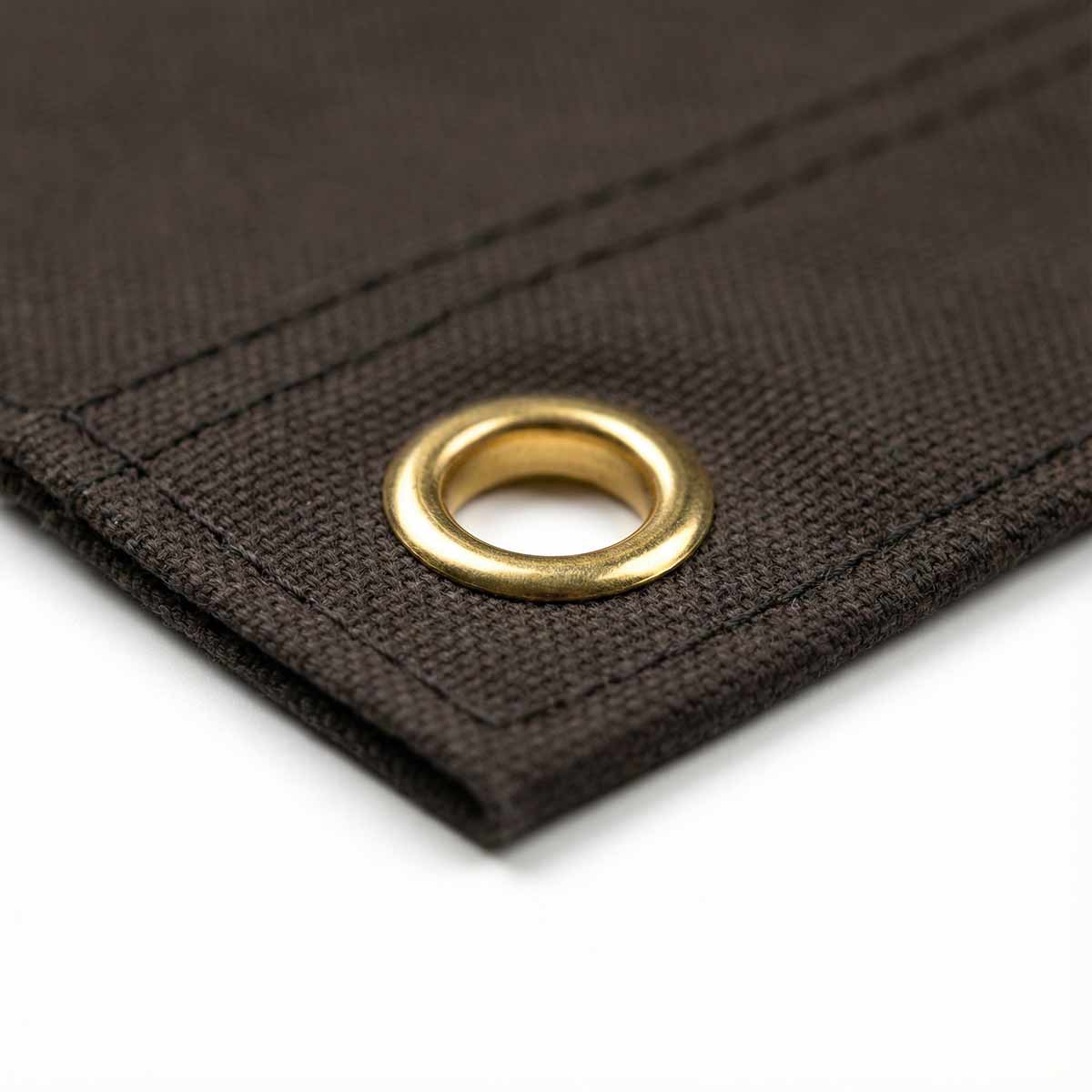 Close-up of black fabric with a brass eyelet on a white background
