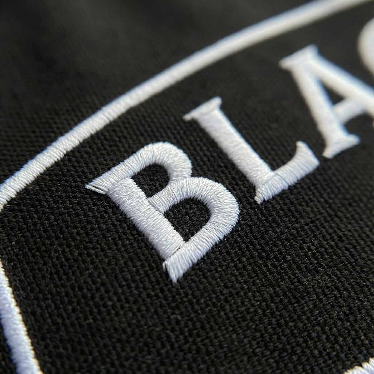 Close-up of the embroidery on the Kraken Blacklist flag with white embroidered text on a dark background