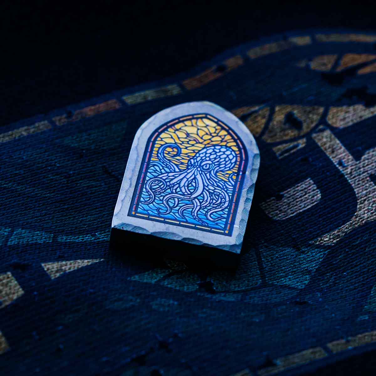titanium stained-glass kraken golf ball marker on black background