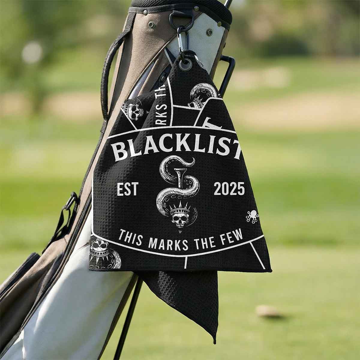 Golf bag with 'Blacklist' towel on a golf course