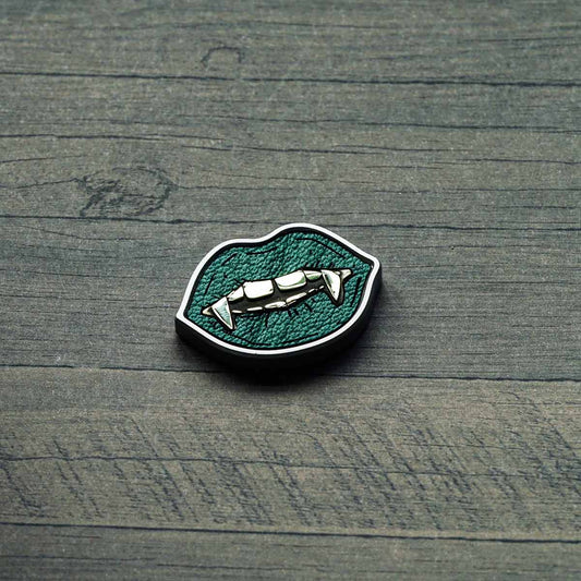 stainless steel golf ball marker with green leather inlay and brass fangs