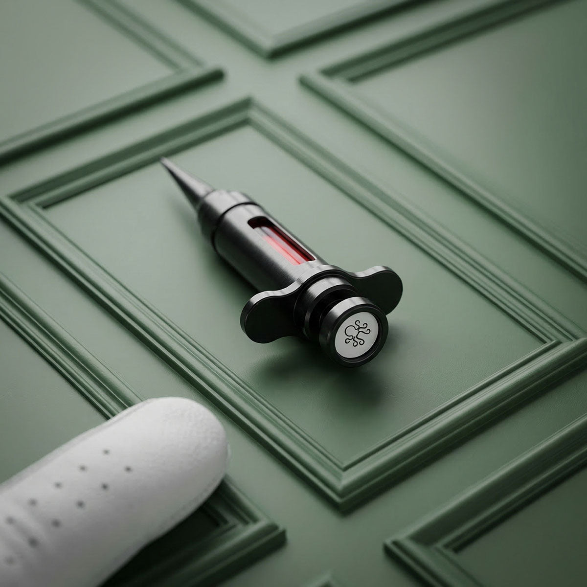 Luxury golf divot repair tool shaped like a syringe in black oxide carbon steel