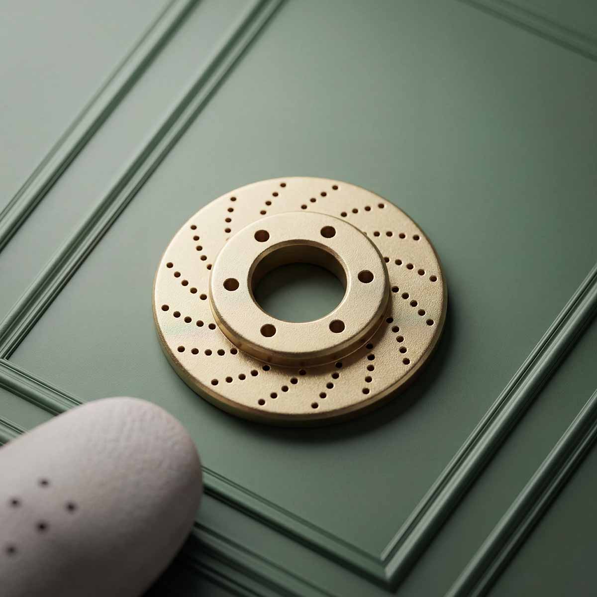 Brake disc ball marker in brass on a green textured surface