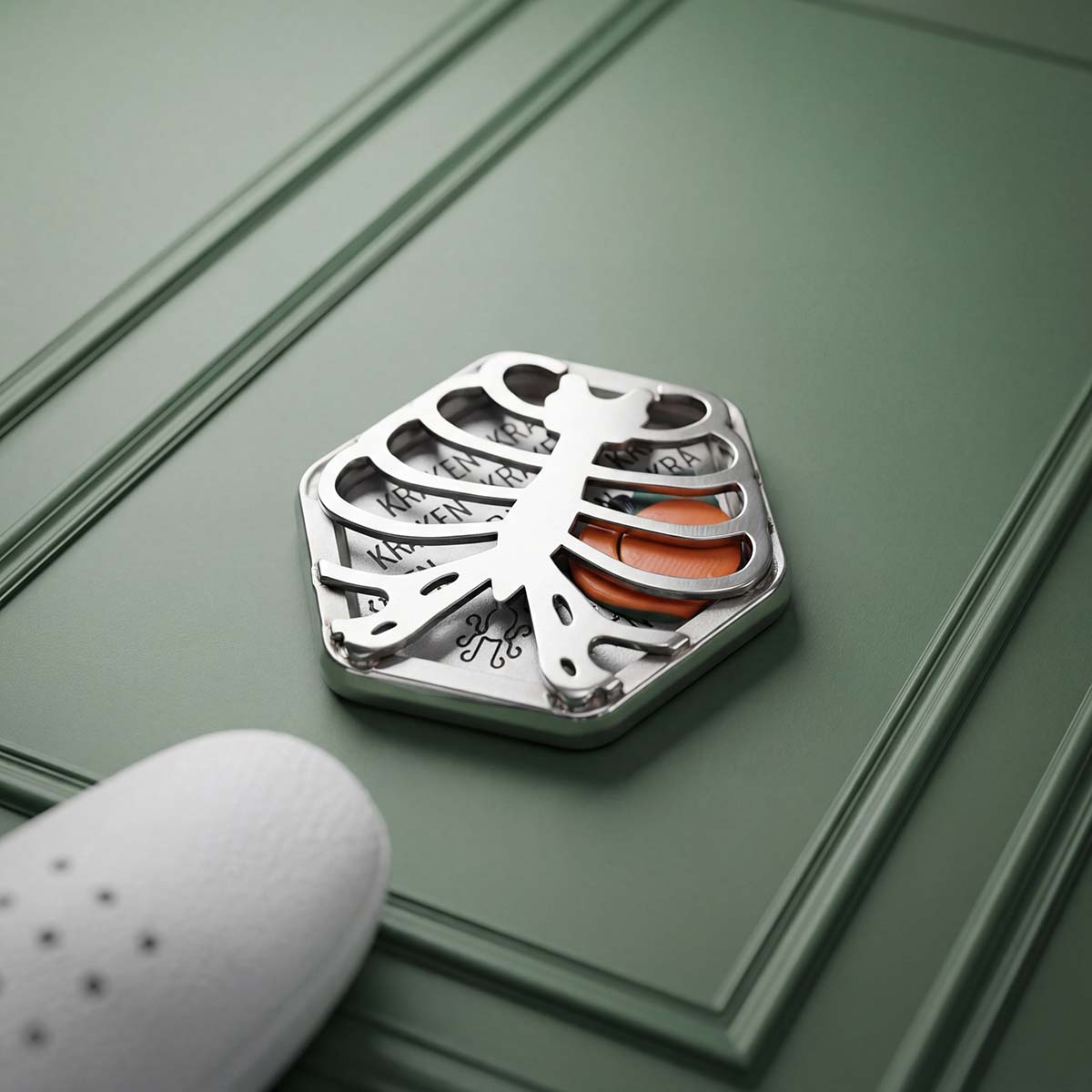 Kraken Golf Caged Peach limited edition stainless steel golf ball marker resting on green panel — 1 of 30 Blacklist exclusive pieces