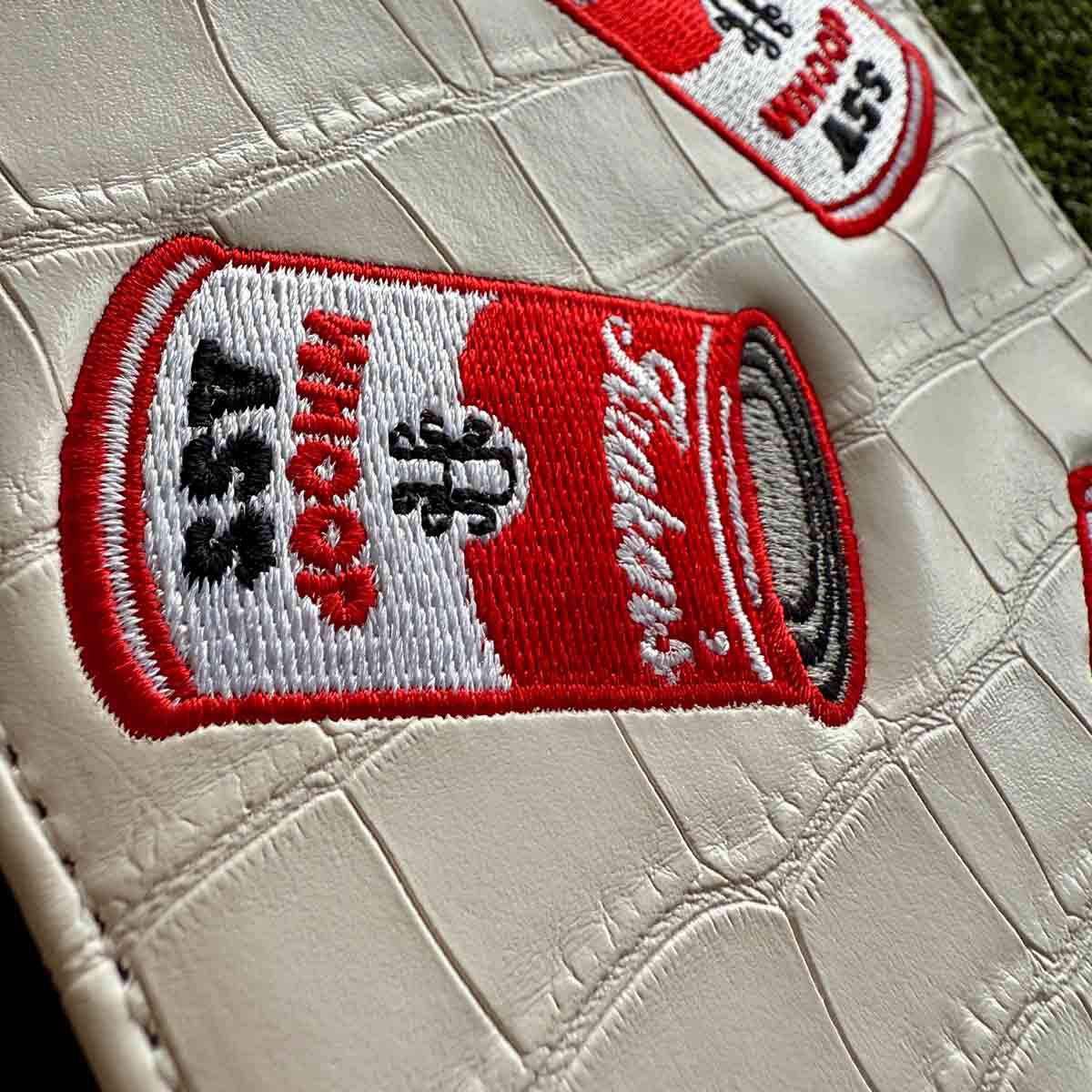 Close-up of embroidered Campbell-inspired Whoop Ass can on golf yardage book holder