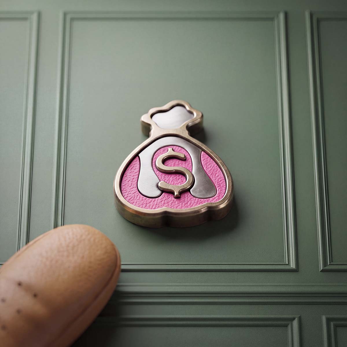 Front of Kraken Golf Compound ball marker, a machined brass money bag with a raised dollar sign over hot-pink drip and stainless steel inlays