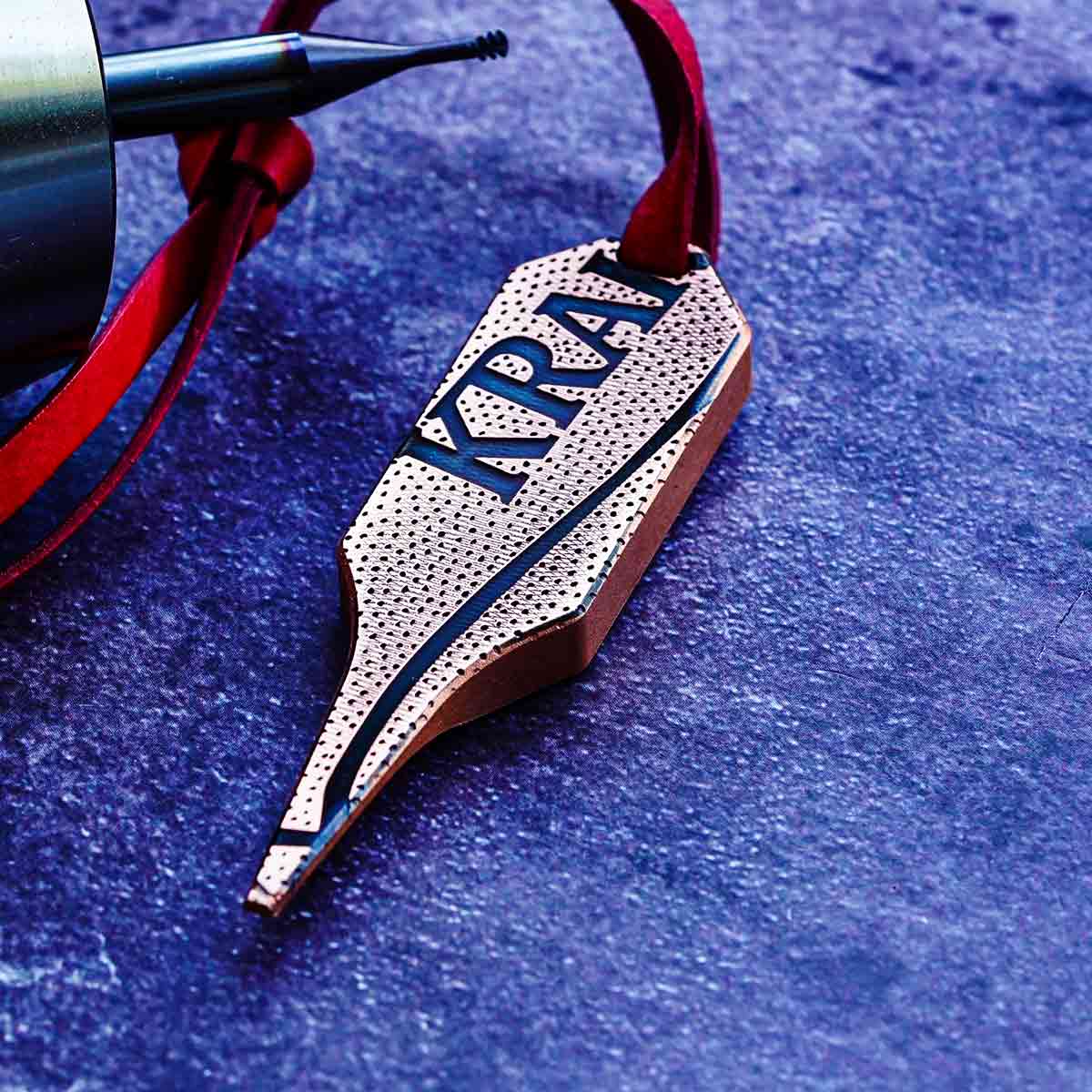 Matte copper pitch tool back with basketball texture and KRAK engraving with leather lanyard