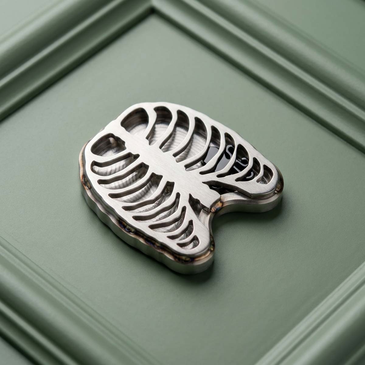Stainless steel golf ball marker rib cage cutout with blackened steel Kraken floating inside the chest cavity — Heartless II by Kraken Golf