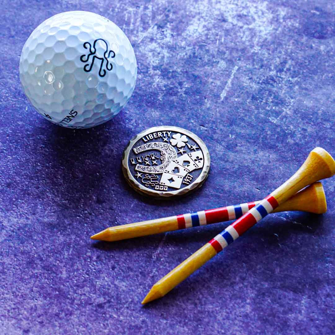 Hand-distressed brass golf ball marker with deep patina finish, engraved "Hobo Luck" design, and hammered edgework. Limited Kraken Golf release.