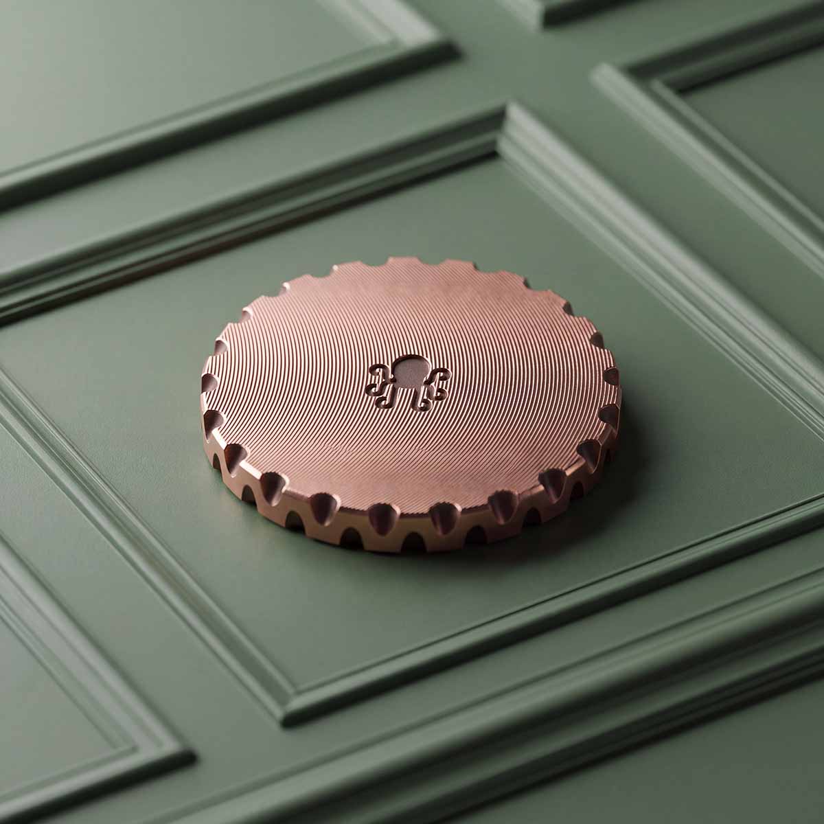 Reverse of HOLLOWED copper golf ball marker showing concentric machined finish and engraved Kraken mark
