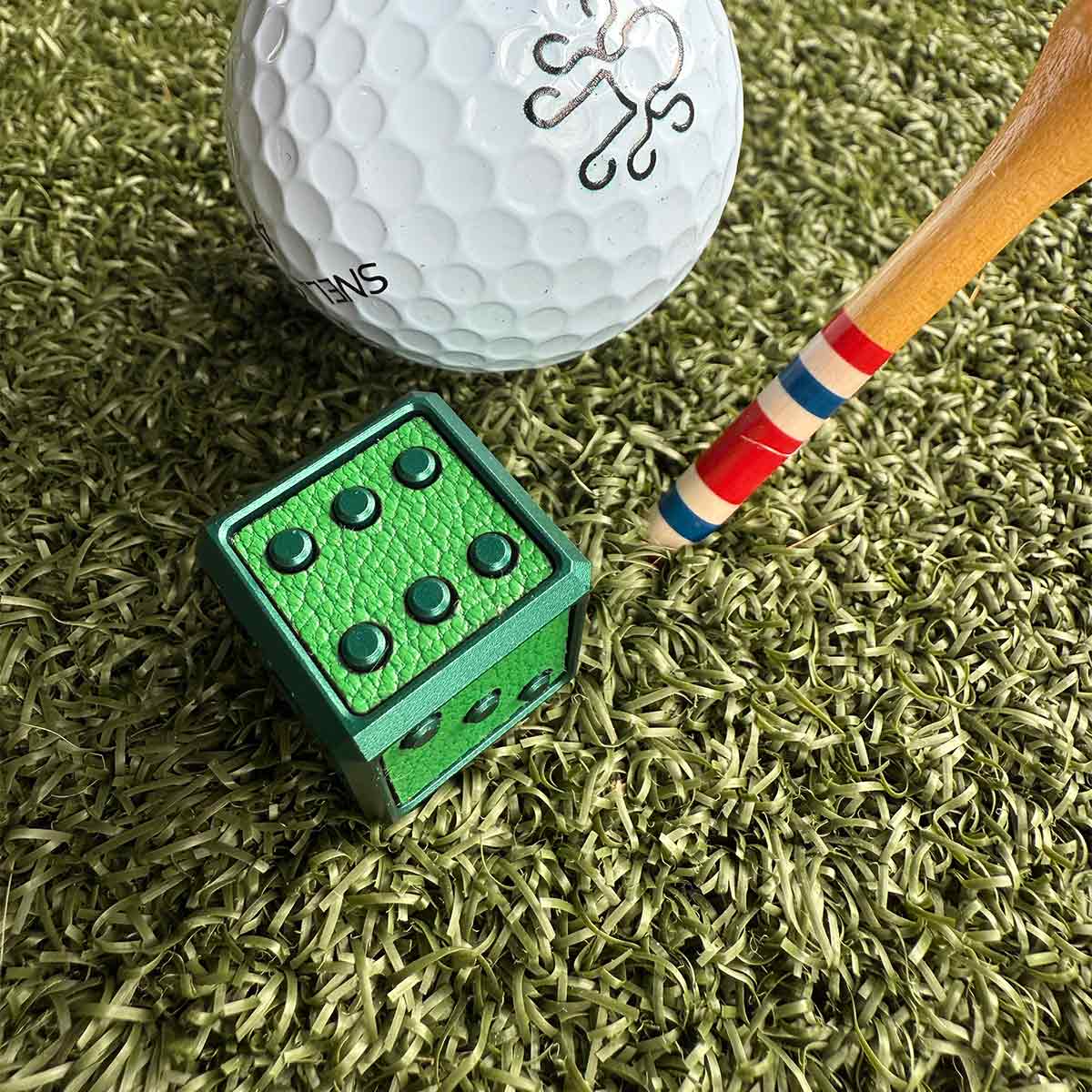 A bold, cube-shaped golf ball marker with green anodized finish and leather inlay - a high-end tool for players who flex on the green.