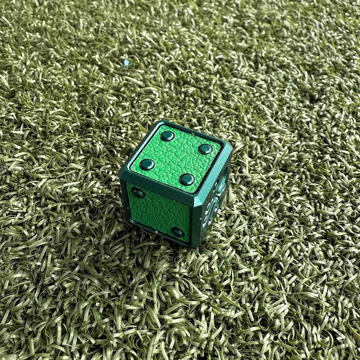 A limited-edition green die golf ball marker featuring deep green anodized aluminum with green French leather inlays. Designed by Kraken Golf.
