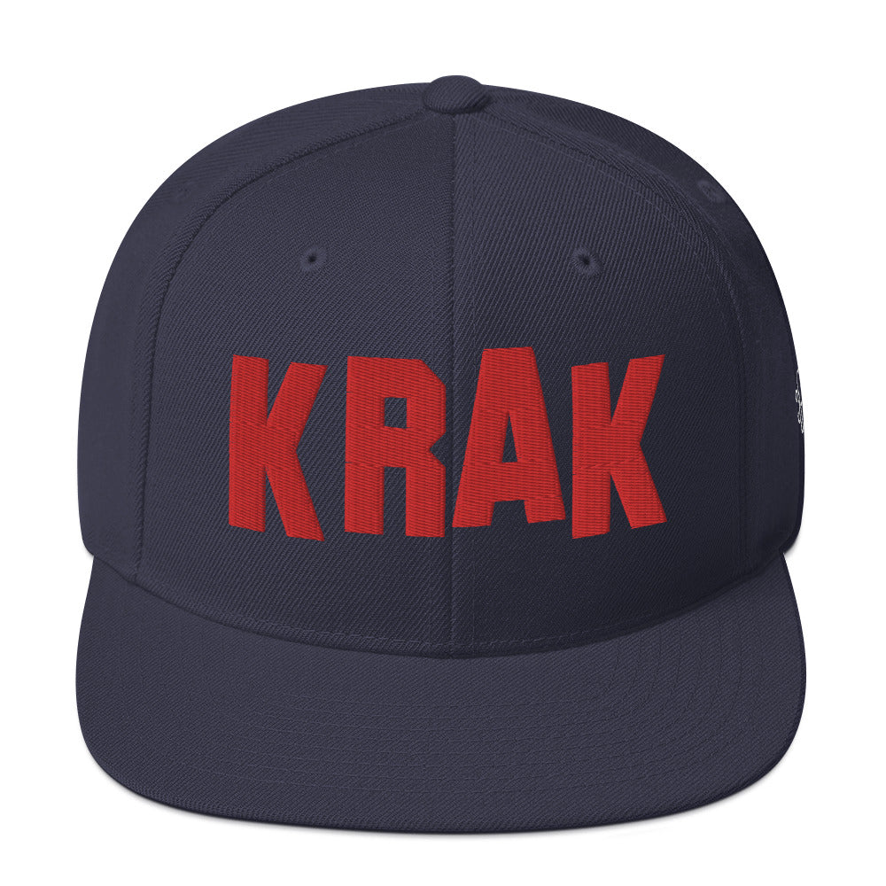 Navy snapback hat with bold red KRAK lettering and green undervisor