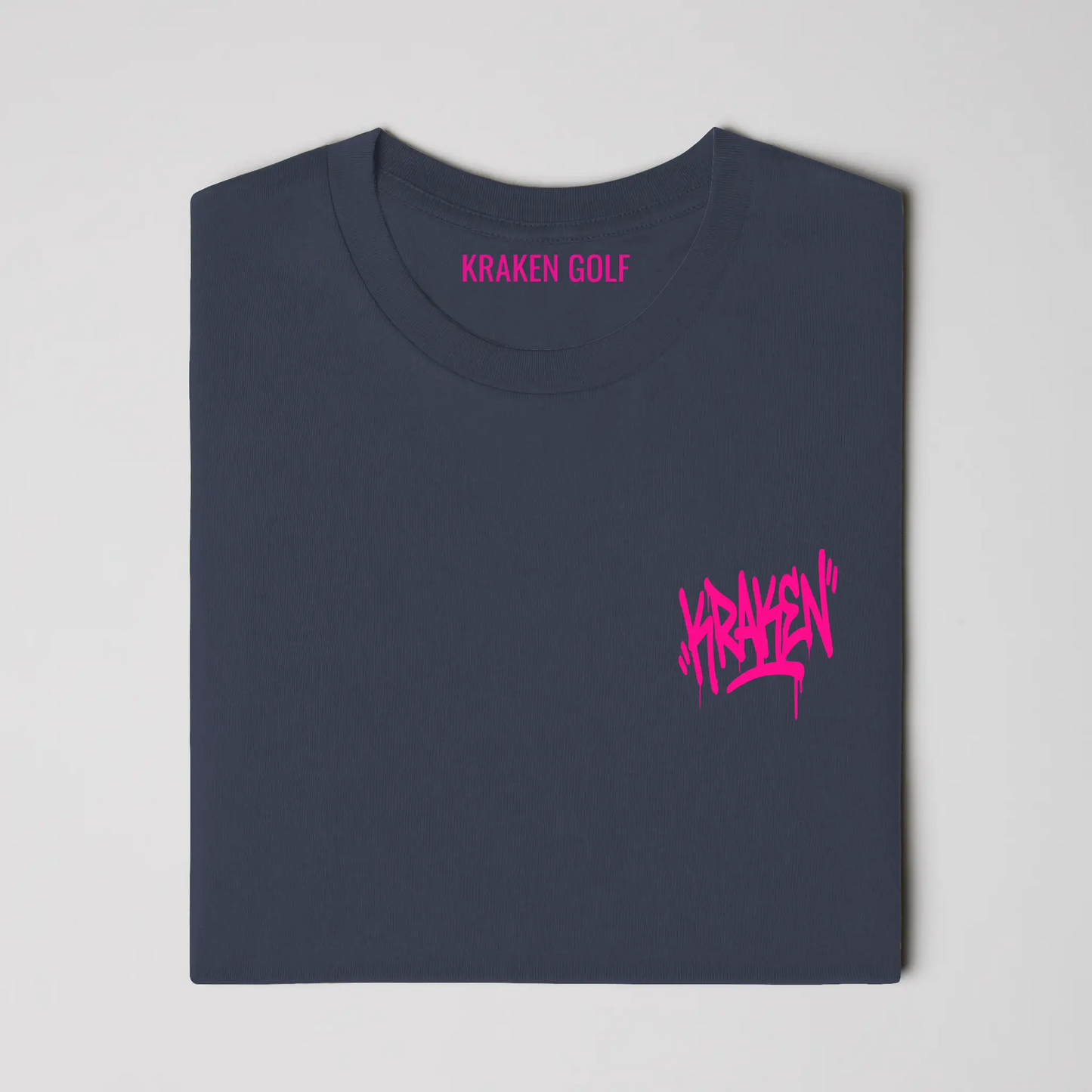 Left chest detail of the navy Origin tee showing the black Kraken graffiti tag on heavyweight garment-dyed cotton