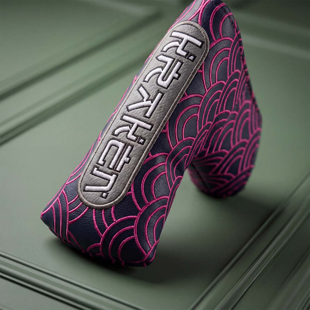 Angled view of navy and pink Seigaiha blade putter headcover showing wave embroidery and toe badge