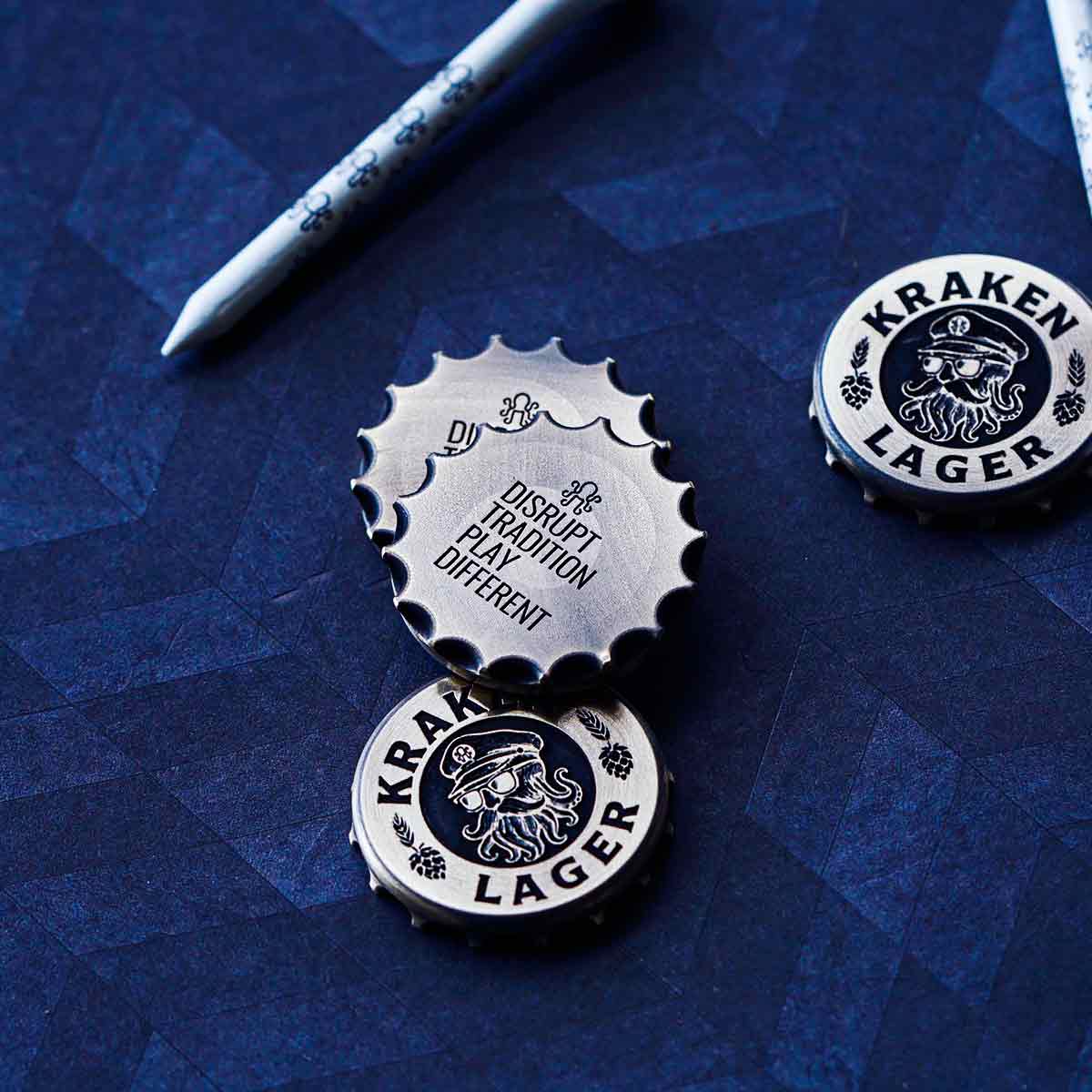 DUSRUPT TRADITION PLAY DIFFERENT back engraving on a bottle cap shaped golf ball marker