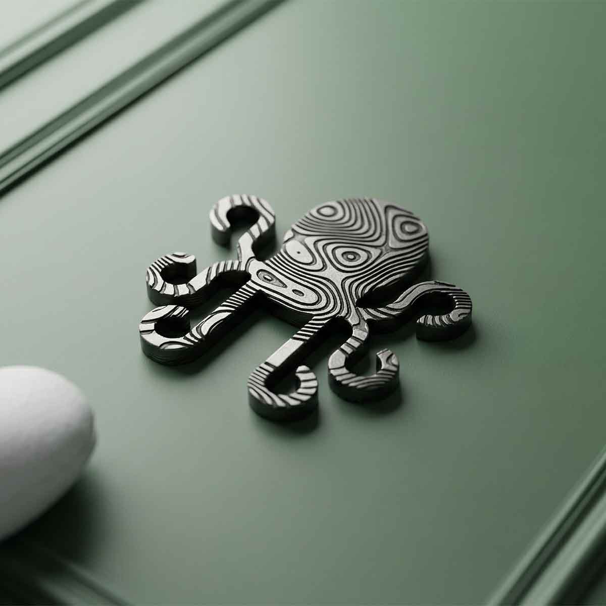 Kraken shaped brass damascus golf ball marker on a green background