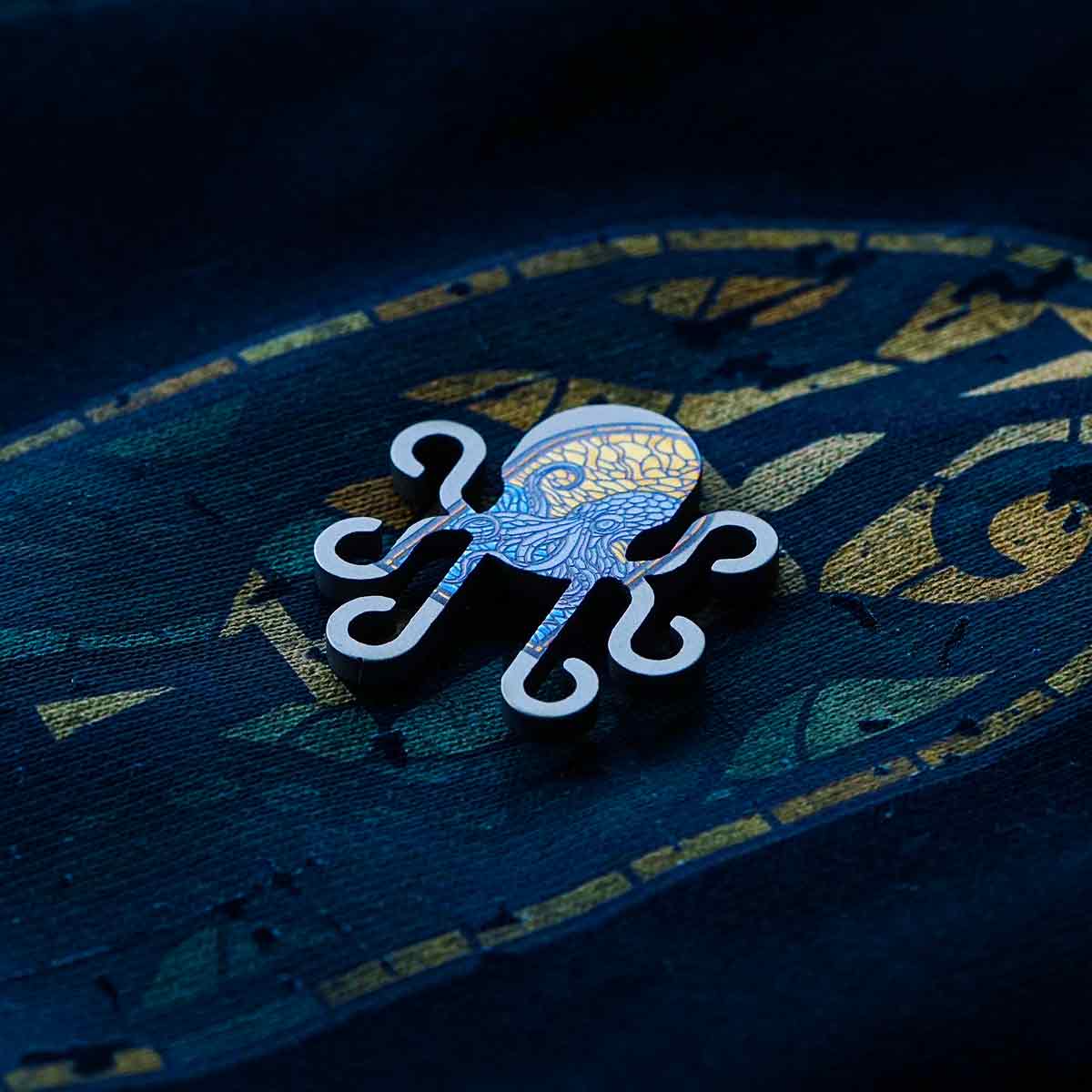 titanium stained-glass kraken golf ball marker on black background